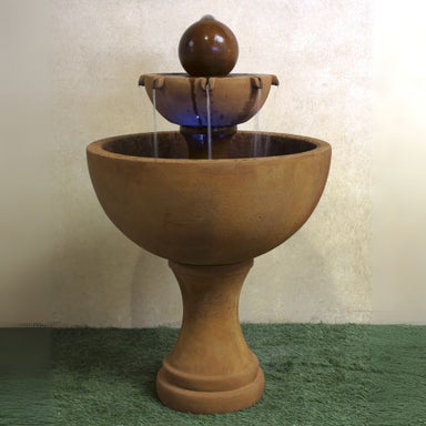 Orbis Two Tier Fountain on grass against brown background.
