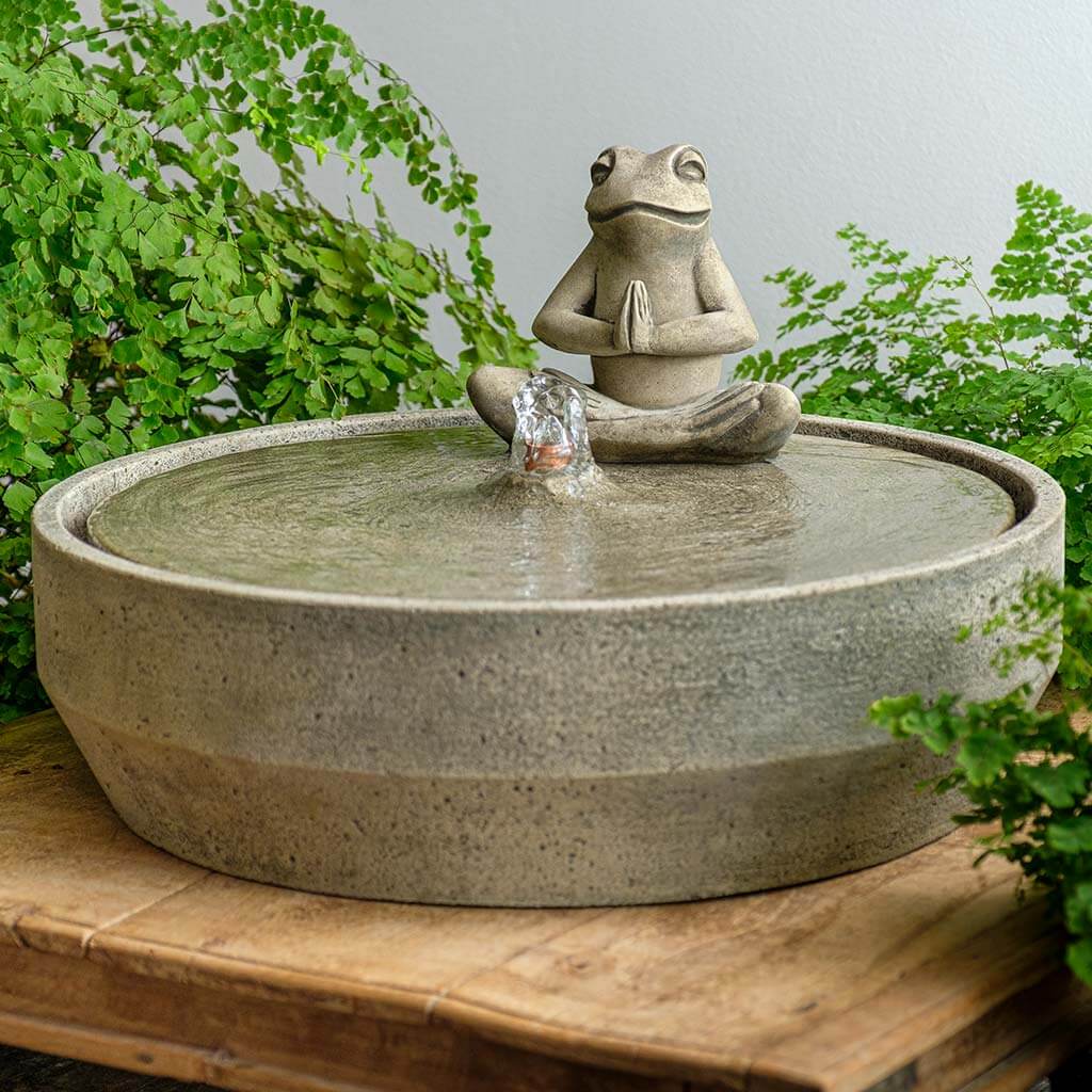 Beveled Yoga Frog Fountain on the table beside green plants