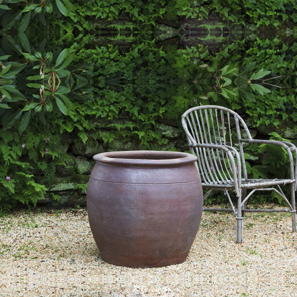 Brown Terra Cotta Planters Collection Image of Mai Planter Black Clay S/1 on gravel beside chair.