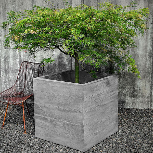 Faux Wood Planters Collection Image of Chenes Brut Box Planter filled with plants beside a chair.