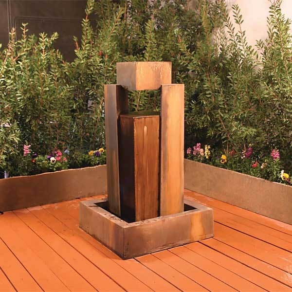 GFRC Fountains Collection Image of Rocket Modern Water Fountain on patio near shrubs.