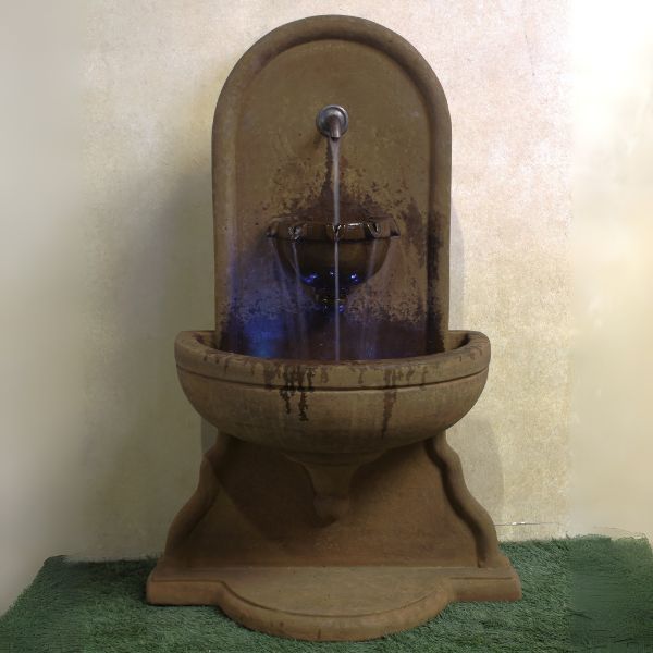 Absolute Wall Fountain on grass against brown background.