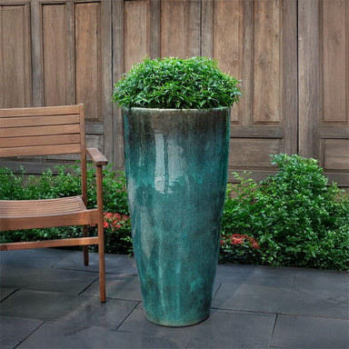Aluan Tall Planter - Antique Jade - on concrete filled with plants.