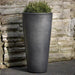 Aluan Tall Planter - Graphite - on concrete filled with plants.
