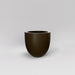 Alzira Round Fiberglass Planter in matte bronze against gray background.