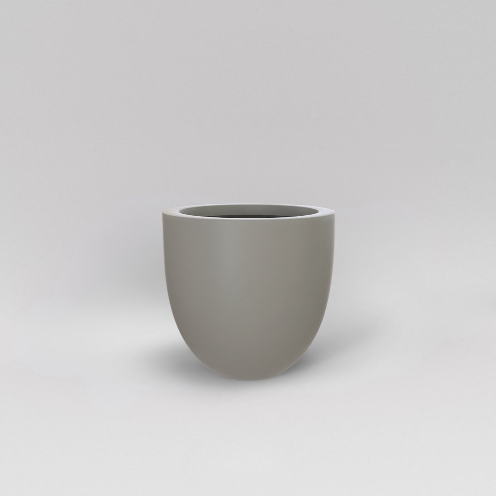 Alzira Round Fiberglass Planter in matte cement grey against gray background.