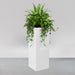 Amesbury Tall Corner Planter filled with plants against gray backdrop