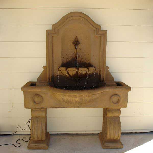 Anduze Wall Fountain Tall on concrete against cream wall.