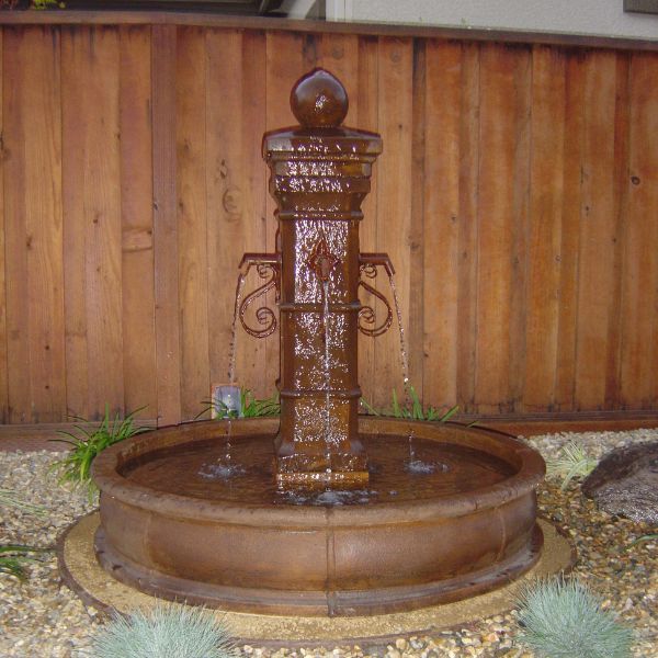 Avignon Pond Fountain in action against wooded fence.