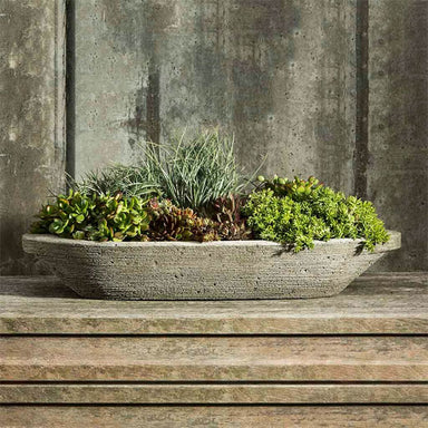 Barca Planter on concrete filled with plants.