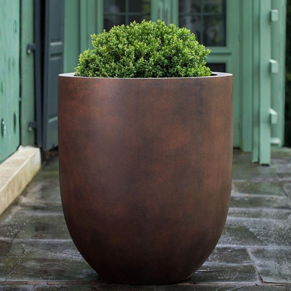 Bradford Planter Extra Large in rust premium color on concrete filled with plants.