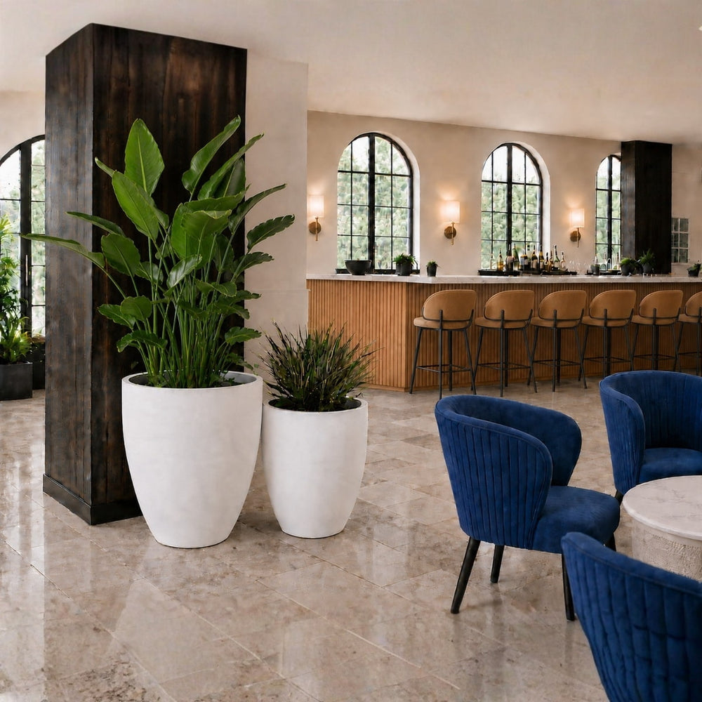 Brannan planters in varying heights in Matte Bright White filled with tropical greenery in a luxury hotel lounge setting
