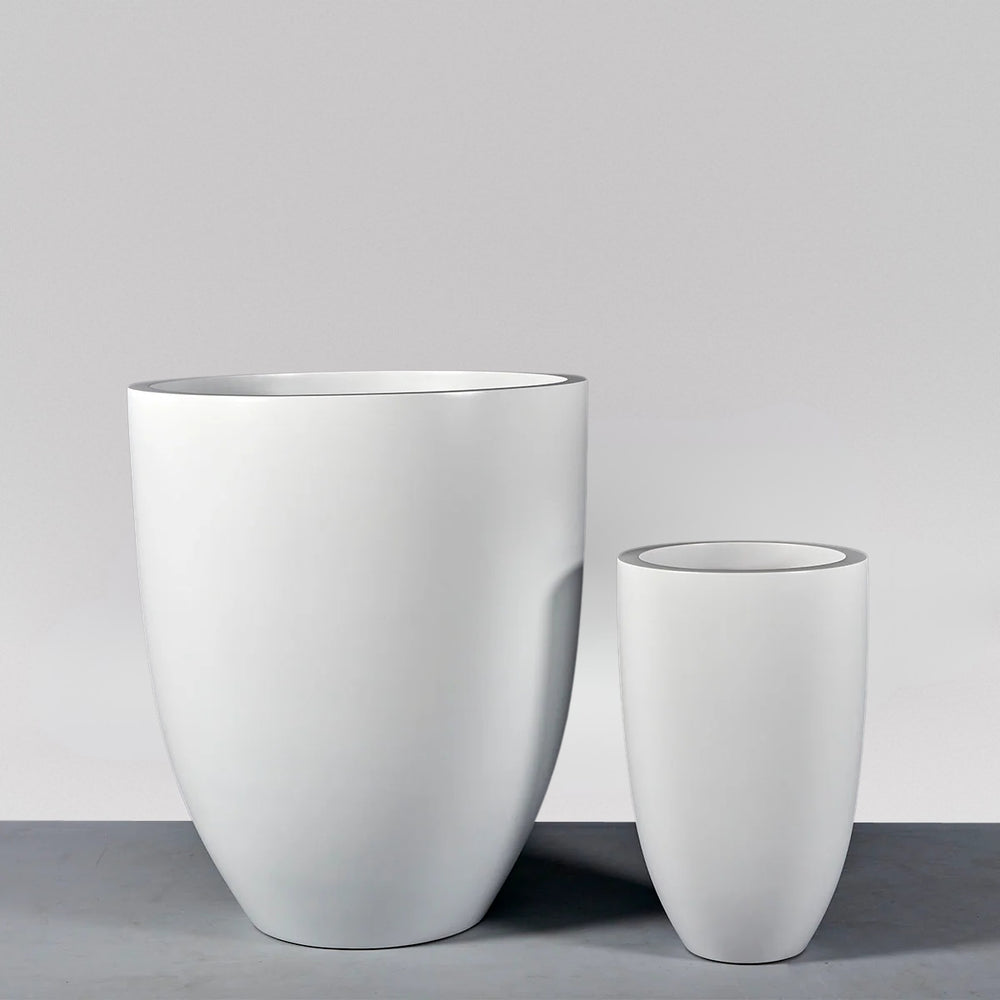 Brannan Tapered Round Fiberglass Planter on concrete shown with different sizes.