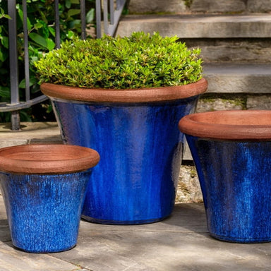 Brighton Planter - Riviera Blue - Set of 3 on concrete filled with plants.