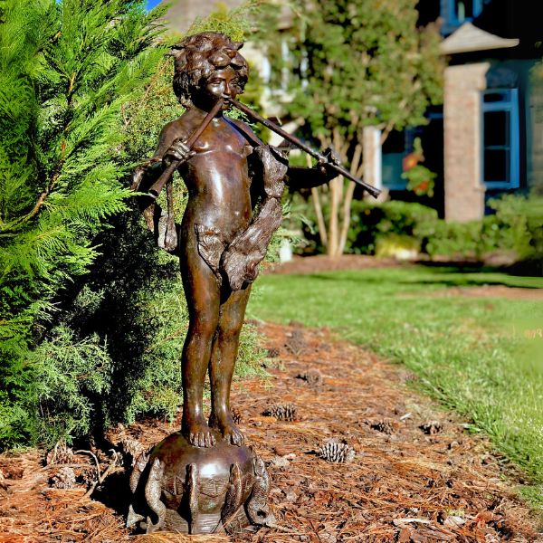 Bronze Boy with pipes on fish base fountain sculpture on ground in the backyard