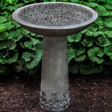 Cirrus Birdbath against green leaves in the backyard