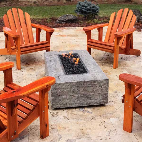 Coronado Wood Grain Fire Pit surrounded by wooden chairs in the backyard