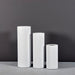 Corry Tall Cylinder Fiberglass Planter on concrete shown in different sizes.