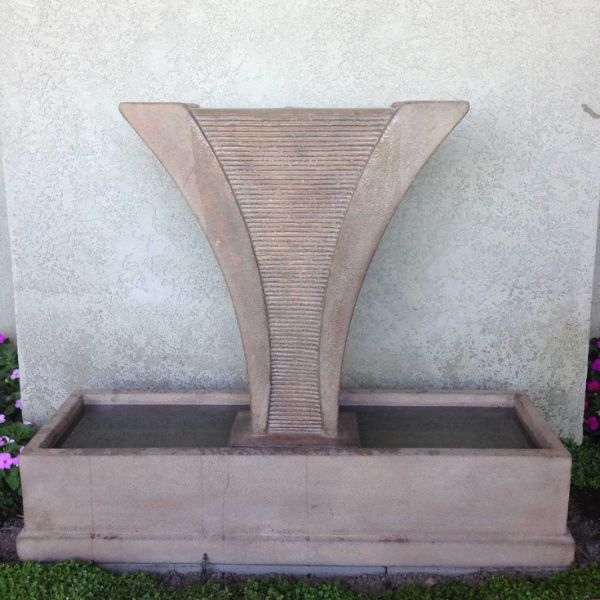 Diesse Fountain with side spillways in action against cream wall.