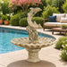 Dolphins with shell bowl fountain in action near a swimming pool.