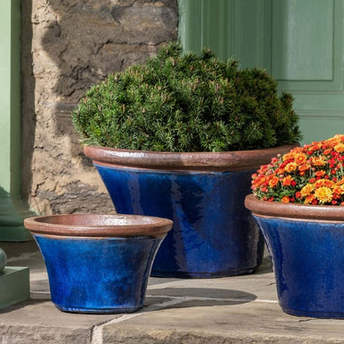 Enfield Planter - Riviera Blue - S/3 on concrete filled with plants.