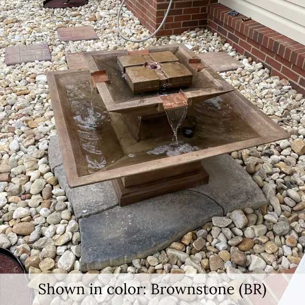 Facet Fountain on concrete surrounded with white pebbles in action.