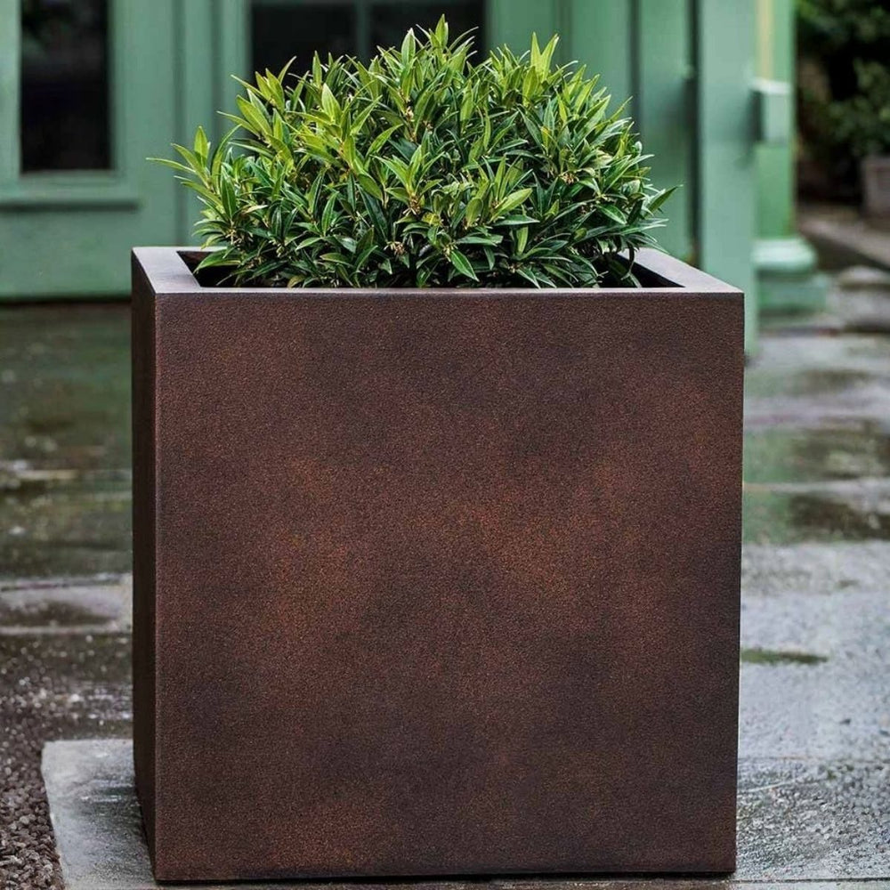 Farnley Planter 3636 S/1 in rust lite on concrete filled with plants.