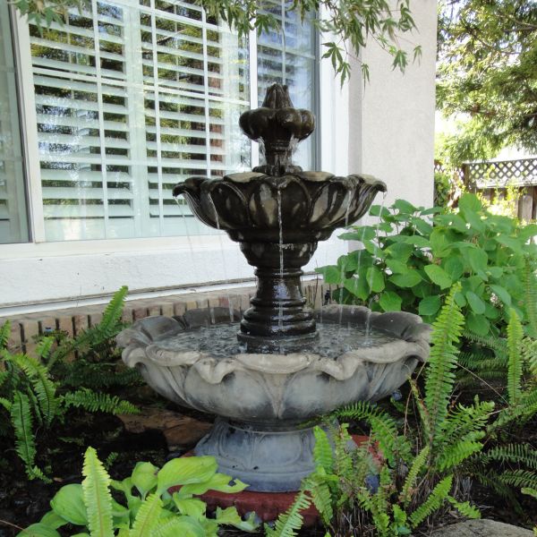 Gardenia Two Tier Fountain Short against the house window.