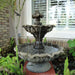 Gardenia Two Tier Fountain Short on concrete in the garden upclose.