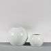 Globe Fiberglass Planter on concrete against gray background.