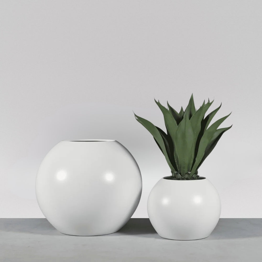 Globe Fiberglass Planter on concrete filled with plants shown with different sizes.