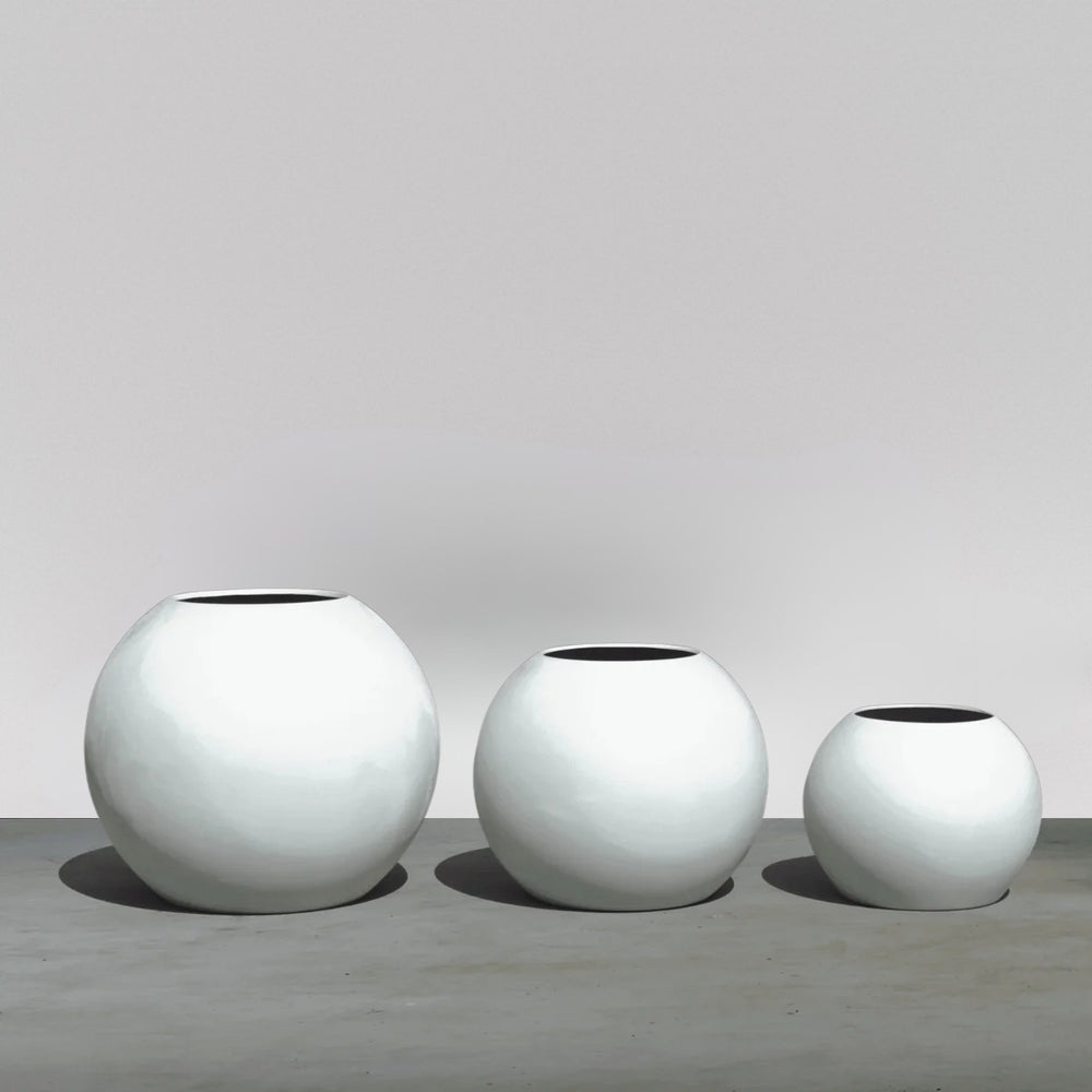 Globe Fiberglass Planter on concrete on concrete shown with different sizes.