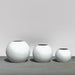 Globe Fiberglass Planter on concrete on concrete shown with different sizes.