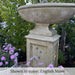 Gramercy Fountain in action beside purple flowers upclose.