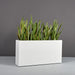 Hollywood Rectangle Fiberglass Planter on concrete filled with plants.