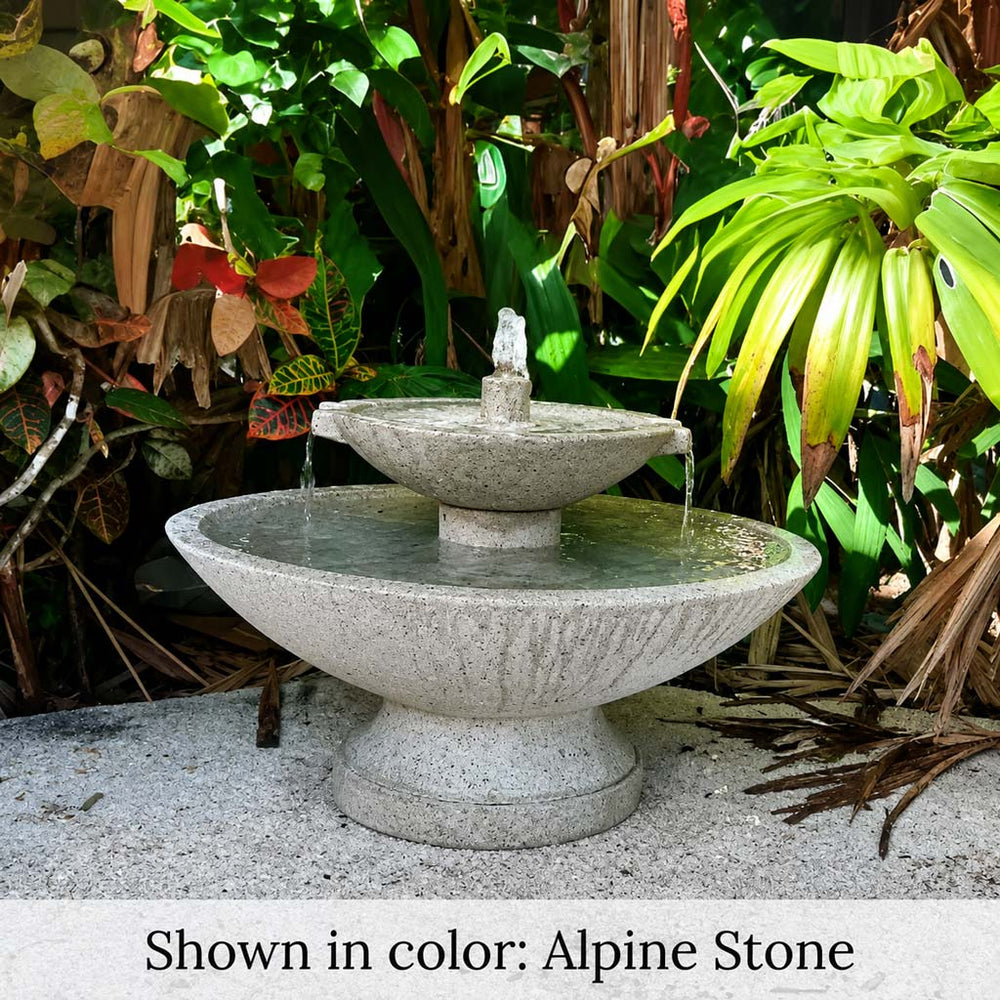 Jensen Oval Fountain on concrete against green plants. 