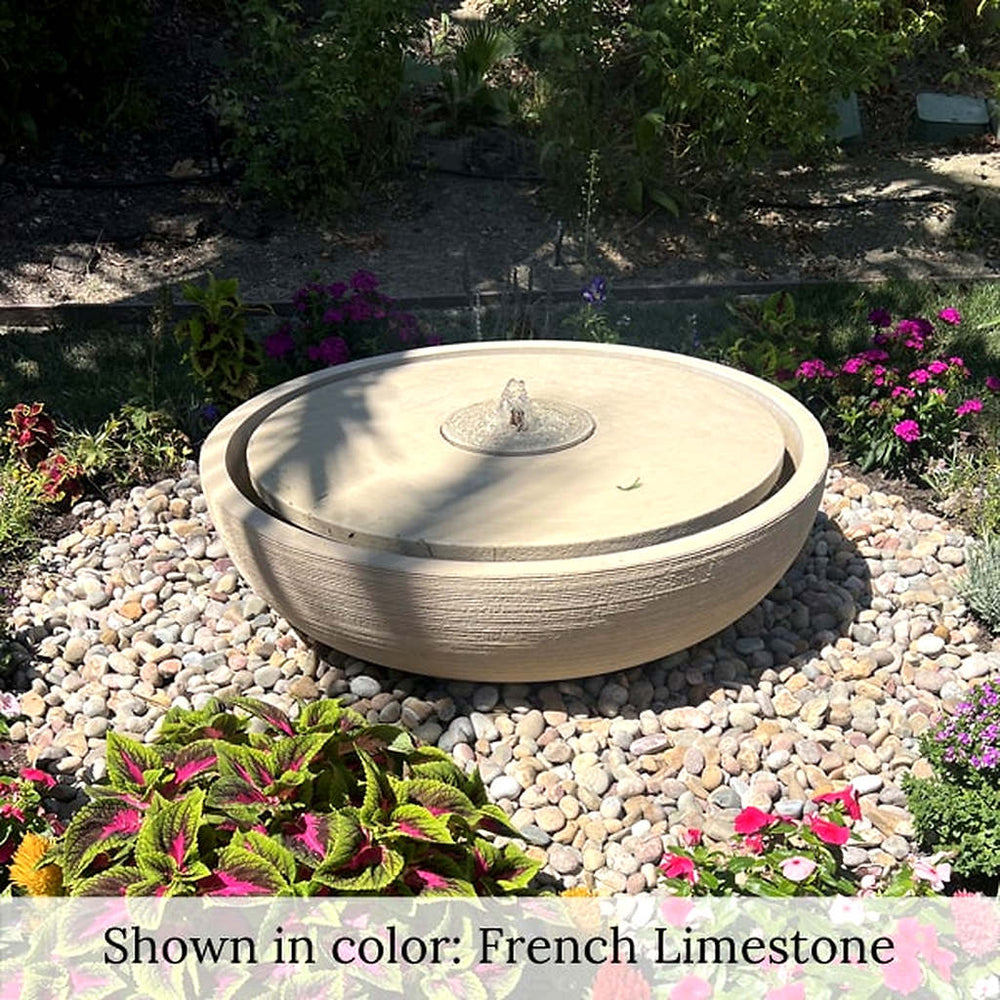 Large Girona Fountain in rock garden surrounded by flowers.