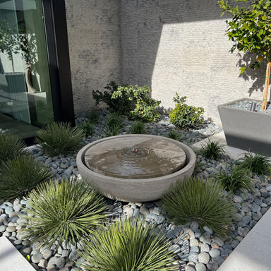 Large Girona modern outdoor water fountain with concrete bowl design in backyard rock garden.