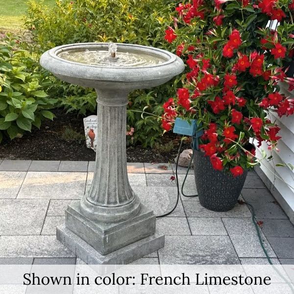 Longmeadow Fountain beside planter with red flowers.