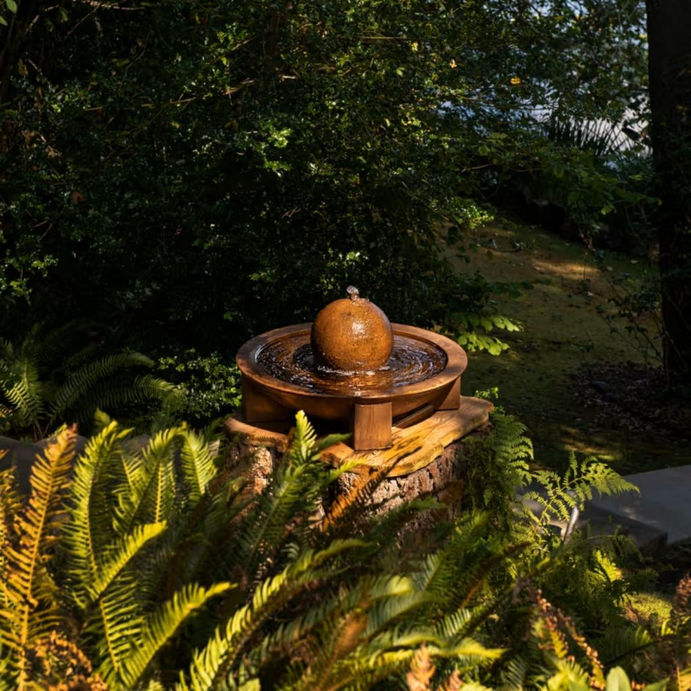 Low Zen Sphere fountain in action on tree stump surrounded by lush greenery
