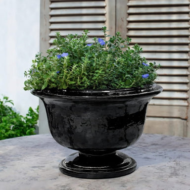 Margaux Urn Planter in obsidian color on table filled with plants.