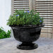 Margaux Urn Planter in obsidian color on table filled with plants.