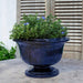 Margaux Urn Planter in riviera blue color on table filled with plants.