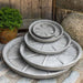 Medium Campania Plant Saucers on concrete in the backyard.
