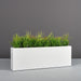 Miami Rectangle Fiberglass Planter on concrete filled with plants.