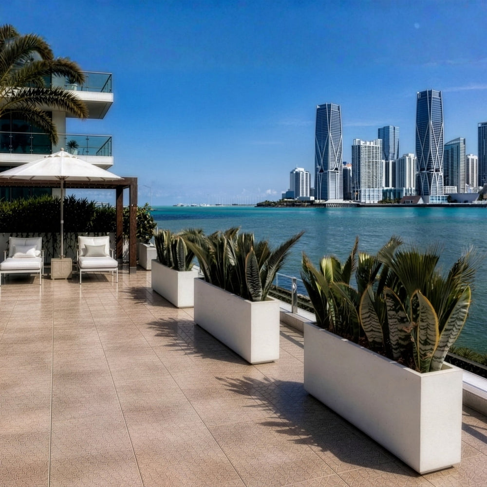 White rectangular Milano planters with snake plants on a luxury waterfront terrace overlooking a modern city skyline.