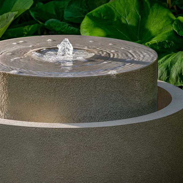 Millstone Fountain on the ground with plants background upclose