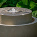 Millstone Fountain on the ground with plants background upclose