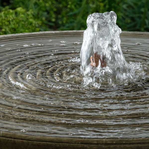 Onda Fountain on concrete with plants background upclose