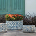 Oriel Planter, Low in glazed murano blue on concrete filled with plants.